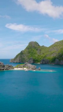 Tapiutan Adası 'nda tekneleri olan bir plaj. Mavi gökyüzü ve bulutlar. El Nido, Palawan. Filipinler. Dikey görünüm.