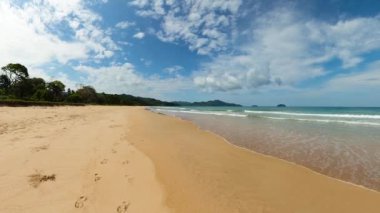 Duli Sahili 'ndeki kumlu sahile açık deniz dalgaları çarpıyor. Mavi gökyüzü ve bulutlar. El Nido. Palawan 'da. Filipinler.