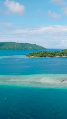 Mavi denizde ve sahilde turkuaz suyu olan adanın insansız hava aracı görüntüsü. Gargantos Plaj Tatil Köyü. Romblon, Filipinler. Dikey görünüm.