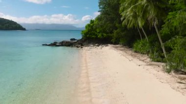 Beyaz kumlu ve berrak okyanus dalgalı tropikal sahilde hindistan cevizi ağaçları. Romblon Adası. Romblon, Filipinler.