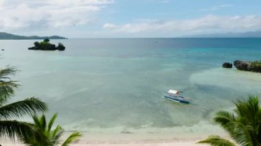 Beyaz sahilde açık deniz suyunda yüzen tekne, Cobrador Adası 'ndaki hindistan cevizi ağaçlarının manzarası. Romblon, Filipinler.