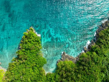 Okyanus dalgaları kayalık kıyı şeridine çarpıyor, turkuaz su ve mercanlar. Carabao Adası. San Jose, Romblon. Filipinler.