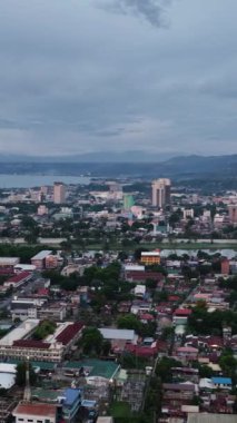 Alacakaranlıkta Cagayan de Oro 'da binalar ve yerleşim alanları. Mindanao, Filipinler. Şehir manzarası. Dikey video.