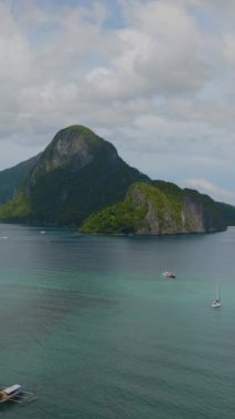 Topical Island ve turistik tekneler turkuaz sularda. El Nido. Palawan, Filipinler. Dikey görünüm.