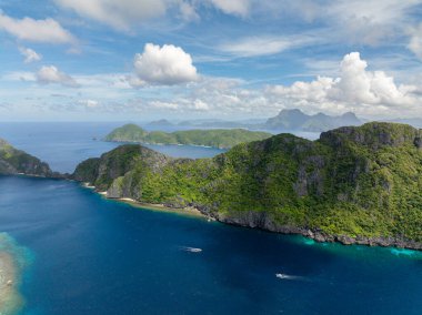 Mavi denizde teknesi olan Matinloc Adası. Mavi gökyüzü bulutları. El Nido, Filipinler.