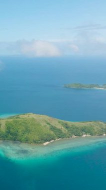Sahilde beyaz kumsal olan Logbon Adası bulutların ötesini görüyor. Romblon, Filipinler. Dikey görünüm.