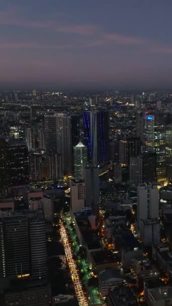 照らされたライトが付いている高層ビル 夜のマカティ シティスケープ メトロ マニラ フィリピン 垂直ビュー — ストック動画
