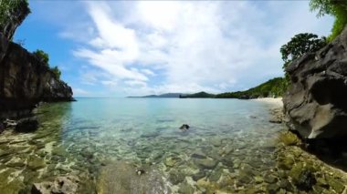 Sahildeki kayaların üzerinde güneş yansıması olan temiz su. Cobrador Adası. Romblon, Filipinler.