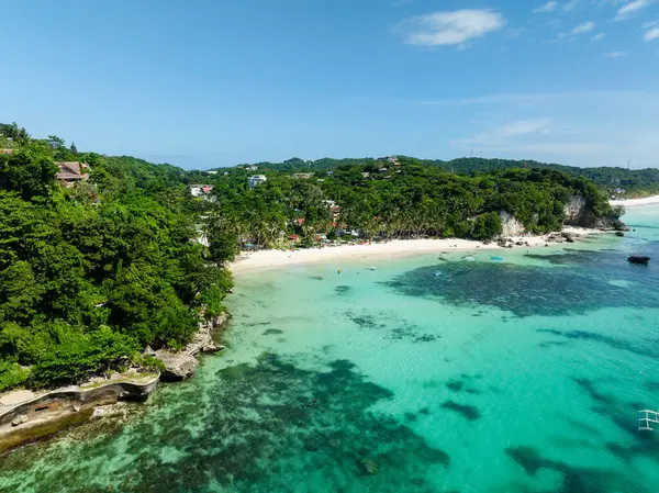 Turkuaz deniz suyunun üzerinde tekneler. Beyaz kumları ve hindistan cevizi ağaçları olan Diniwid Plajı. Boracay, Filipinler.