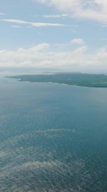 Mavi deniz, güneş yansıması ve mavi gökyüzü ve bulutların altında Carabao Adası. Romblon, Filipinler. Dikey görünüm.