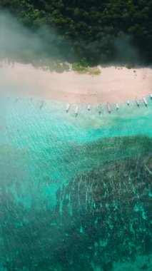 Puka Shell Sahili 'nde sisler ve kıyılarda yüzen tekneler. Boracay, Filipinler. Dikey görünüm.