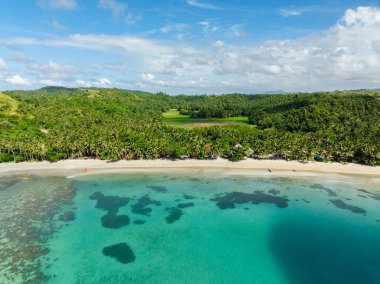 Hindistan cevizi ağaçları ve beyaz kumsallı bir tatil köyü. Mavi gökyüzü ve bulutlar. Santa Fe, Tablas, Romblon. Filipinler.