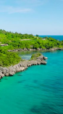 Kıyı şeridinde kayalıklı turkuaz deniz suyu. Mavi gökyüzü ve bulutlar. Carabao Adası. San Jose, Romblon. Filipinler. Dikey görünüm.