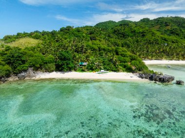 Cobrador Adası 'ndaki kumlu sahilde tekne, yeşilimsi su ve dalgalar. Romblon, Filipinler.