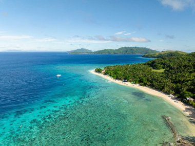 Açık deniz suyu ve dalgaları olan kumsal. Mavi gökyüzü ve bulutlar. Logbon Adası. Romblon, Filipinler.