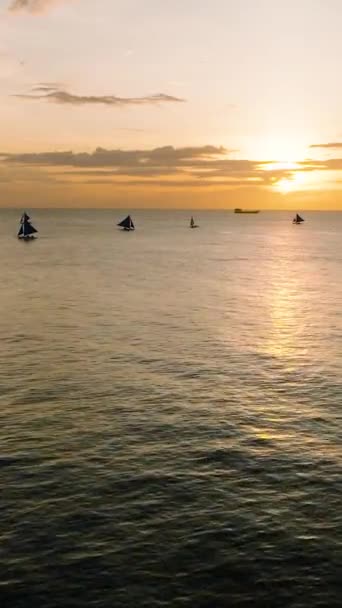 日没の反射で海を飛び回る フィリピンのボラカイでセーリングボート 垂直ビュー — ストック動画