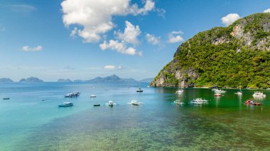 Boats over turquoise clear water with corals in shoreline. El Nido, Philippines. clipart