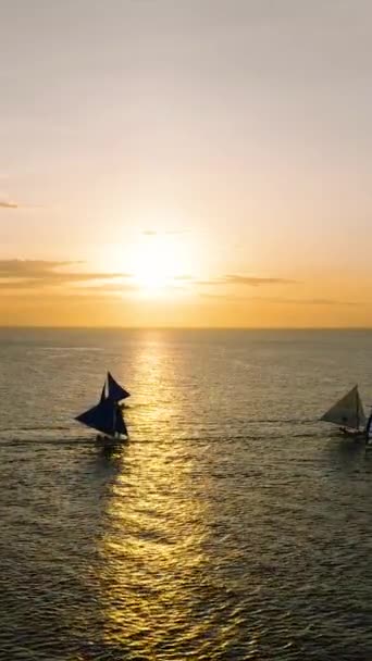 セーリングボートと海の上の曇った夕日 フィリピン ボラカイ 垂直ビュー — ストック動画