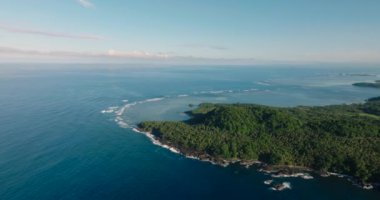 Surigao del Sur 'daki kayalık kıyılarda güzel dalgalar. Mavi gökyüzü ve bulutlar. Surigao del Sur, Filipinler.