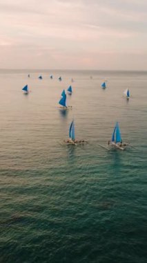 Günbatımında Boracay, Filipinler 'de turkuaz sularda yüzen tekneler. Dikey görünüm.