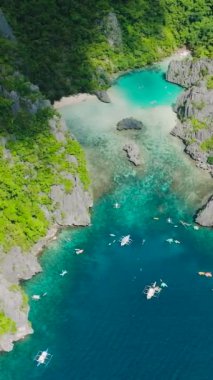 Yeşil suları ve denizde yüzen tekneleri olan bir göl. Cadlao Adası. El Nido. Palawan, Filipinler. Dikey görünüm.