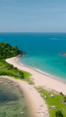 Nacpan Sahili 'ndeki kumlu sahilde güzel dalgalar. İkiz Sahilde tekneler. El Nido, Palawan. Filipinler. Dikey görünüm.