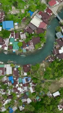 Surigao del Sur 'daki Bogac Soğuk Baharı boyunca evler ve balıkçı tekneleri. Filipinler. Dikey görünüm.
