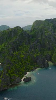 Miniloc Adası 'nın sahil şeridinde beyaz kumsalda tekneler. El Nido, Palawan. Filipinler. Dikey görünüm.