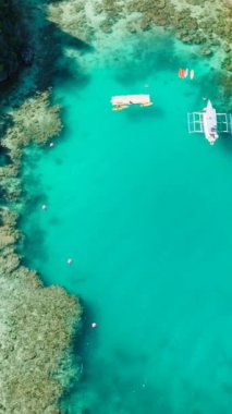 Miniloc Adası 'nda kayık ve kayıkla beyaz kumsal ve turkuaz göller. El Nido, Filipinler. Palawan 'da. Dikey görünüm.
