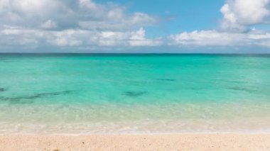 Kumlu sahilde okyanus dalgaları. Mavi gökyüzü ve bulutlar. Puka Sahili. Boracay, Filipinler.