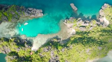 Miniloc Adası 'ndaki gölcüklerin üzerinde güneş yansıması. Kano ve tekneler turkuaz suyun üzerinde. El Nido, Filipinler. Palawan.