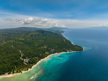 Beyaz kumları ve ağaçları olan tropik bir sahil. Şeffaf gök mavisi su ve mercanlar. Samal Adası. Davao, Filipinler.