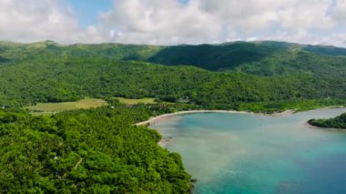 Kumsal ve turkuaz deniz suyuyla adanın insansız hava aracı manzarası. Mavi gökyüzü ve bulutlar. Romblon, Romblon. Filipinler.