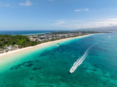 Dalgalar ve turkuaz deniz suyunun üzerinden geçen teknelerle dolu toz beyazı kumsal. Boracay Adası. Filipinler.