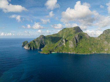 Kumsalı ve mavi denizi olan Cadlao Adası. Mavi gökyüzü ve bulutlar. El Nido, Filipinler.