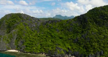 Beyaz kumlu plaj ve Matinloc Adası 'ndaki kireçtaşı kayaları. El Nido, Palawan. Filipinler.