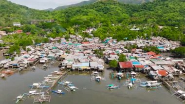 Balıkçı tekneleri ve dikiş evleri. Dağ yamacında yeşil bitkilerle dolu bir kasaba. Koron. Palawan, Filipinler.