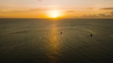Tropik deniz yüzeyinde gün batımı. Gün batımını yansıtan tekneler. Boracay, Filipinler.
