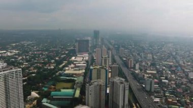 Şehrin üzerinde bulutlu bir gökyüzü, binalar ve metro Manila Skyway. Makati, Filipinler.
