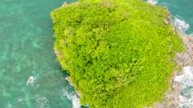 Yukarıdan, turkuaz deniz suyu ve dalgalarla çevrili yeşil bitkilerle çevrili bir ada. Boracay, Filipinler.