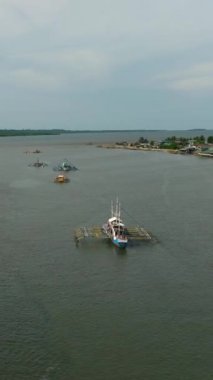 Nehir kıyısında yüzen geleneksel balıkçı tekneleri, nehir kıyısındaki stilt evler. Bislig, Surigao del Sur. Filipinler. Dikey görünüm.