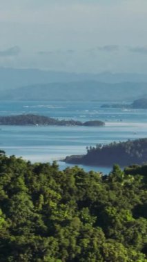 Yeşil ağaçları ve okyanus dalgaları olan tropik adalar. Mindanao, Filipinler. Görüntüyü yakınlaştır. Dikey, hikayeler.