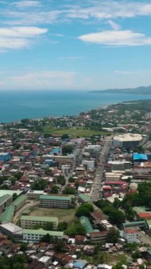 Iligan şehrinin panorama drone görüntüsü. Mavi gökyüzü ve bulutlar. Kuzey Mindanao, Filipinler. Dikey video.