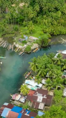 Tropikal orman ve balıkçı evleriyle çevrili Bogac Soğuk Baharı manzarası. Surigao del Sur. Filipinler. Dikey görünüm.