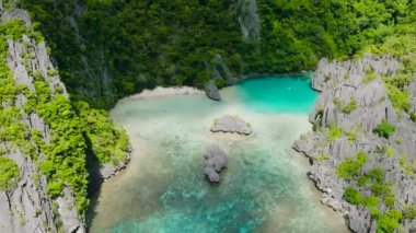 Beyaz kumlu sahil ve kireçtaşı taşlı turkuaz göl. Cadlao Adası. El Nido. Palawan, Filipinler.