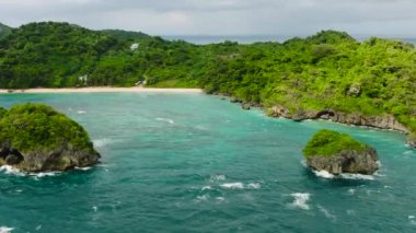 Turkuaz deniz suyu ve dalgalar Ilig Iligan Sahili 'nde kayalara ve kıyılara çarpıyor. Boracay, Filipinler.