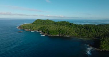 Yeşil ağaçları ve okyanus dalgaları olan tropik bir ada. Surigao del Sur, Filipinler.