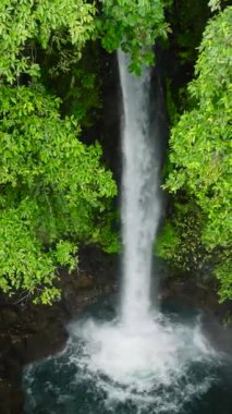 Bereketli yeşilliklerle çevrili soğuk ve tatlı suyla Tuasan Şelalesi. Camiguin Adası. Filipinler. Dikey video.