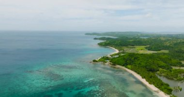 Turkuaz deniz suyu ve mercanlı beyaz kumsal. Santa Fe, Tablas, Romblon 'daki tarım arazileri ve yeşil ağaçlar. Filipinler.