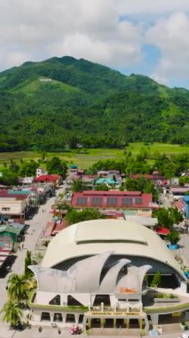 Dağın eteklerinde modern binalar ve yerleşim alanları olan bir şehir. San Agustin, Romblon. Filipinler. Dikey görünüm.